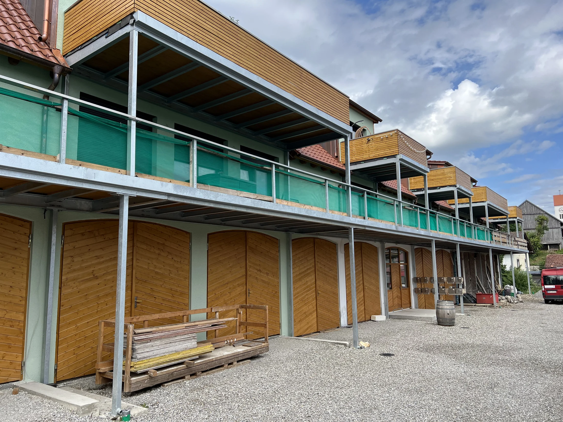 Lange Balkonanlage mit Stahlkonstruktion, Holzverkleidung und Glasgeländern